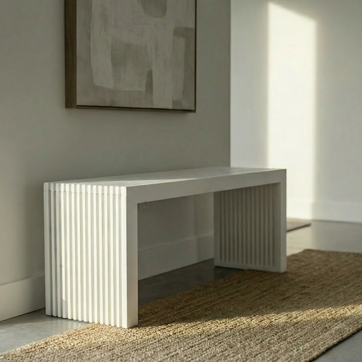 A modern white entryway console table with fluted side panels, styled in a minimalist room with a woven jute rug, neutral wall art, and soft natural light.
