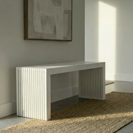 A modern white entryway console table with fluted side panels, styled in a minimalist room with a woven jute rug, neutral wall art, and soft natural light.